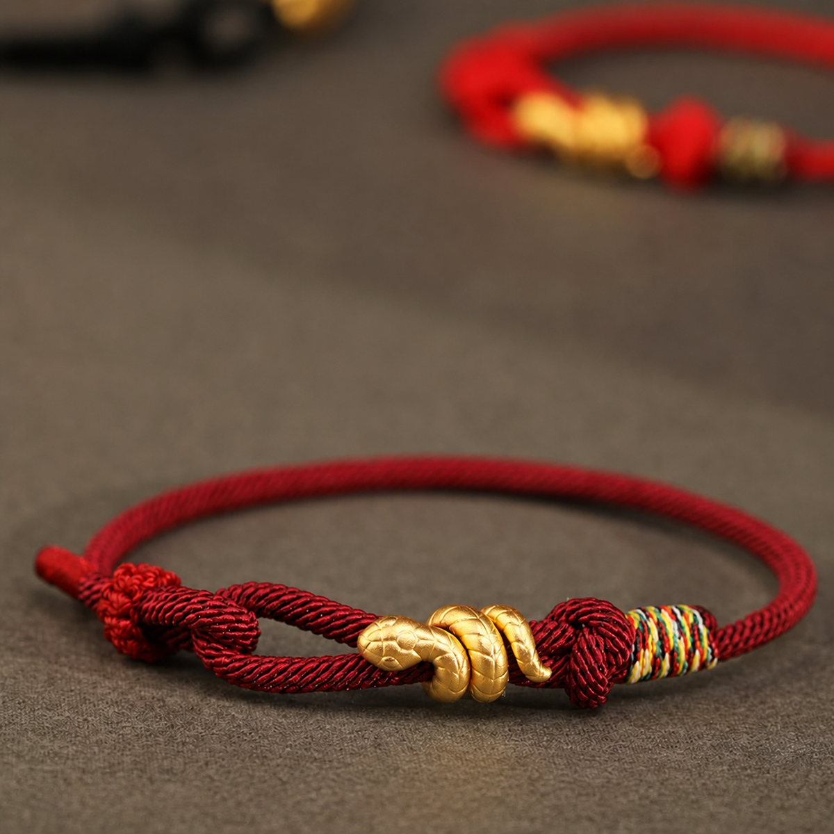 Snake motif bracelet with red, bright red, or black braided cord